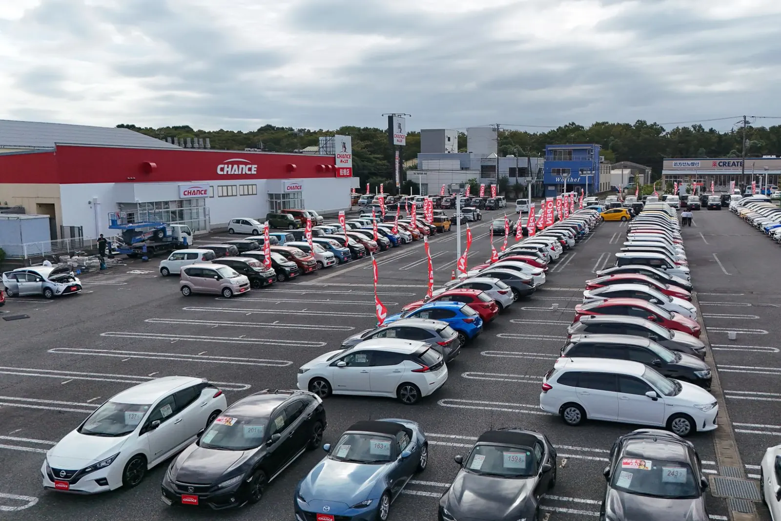 チャンス船橋店の展示場に並ぶ中古車と、お店の建物
