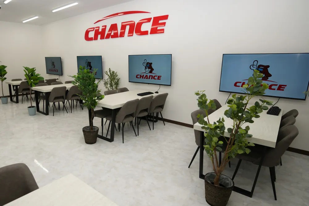 チャンス神栖2号店の店内。商談用のテーブルと観葉植物、壁に並ぶ大型モニター
